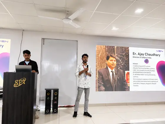A student at the microphone introducing the Director of SSS India from a slide on screen