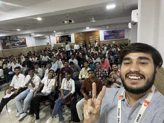 A SSS trainer taking a selfie at the front of a hall, the whole batch behind him with hands raised